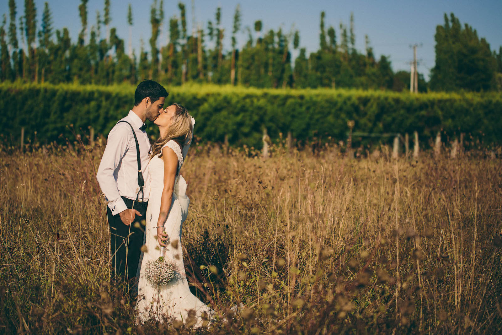 BRIDE-AND-GROOM-KISSING-IN-TUSSOCK-FIELD