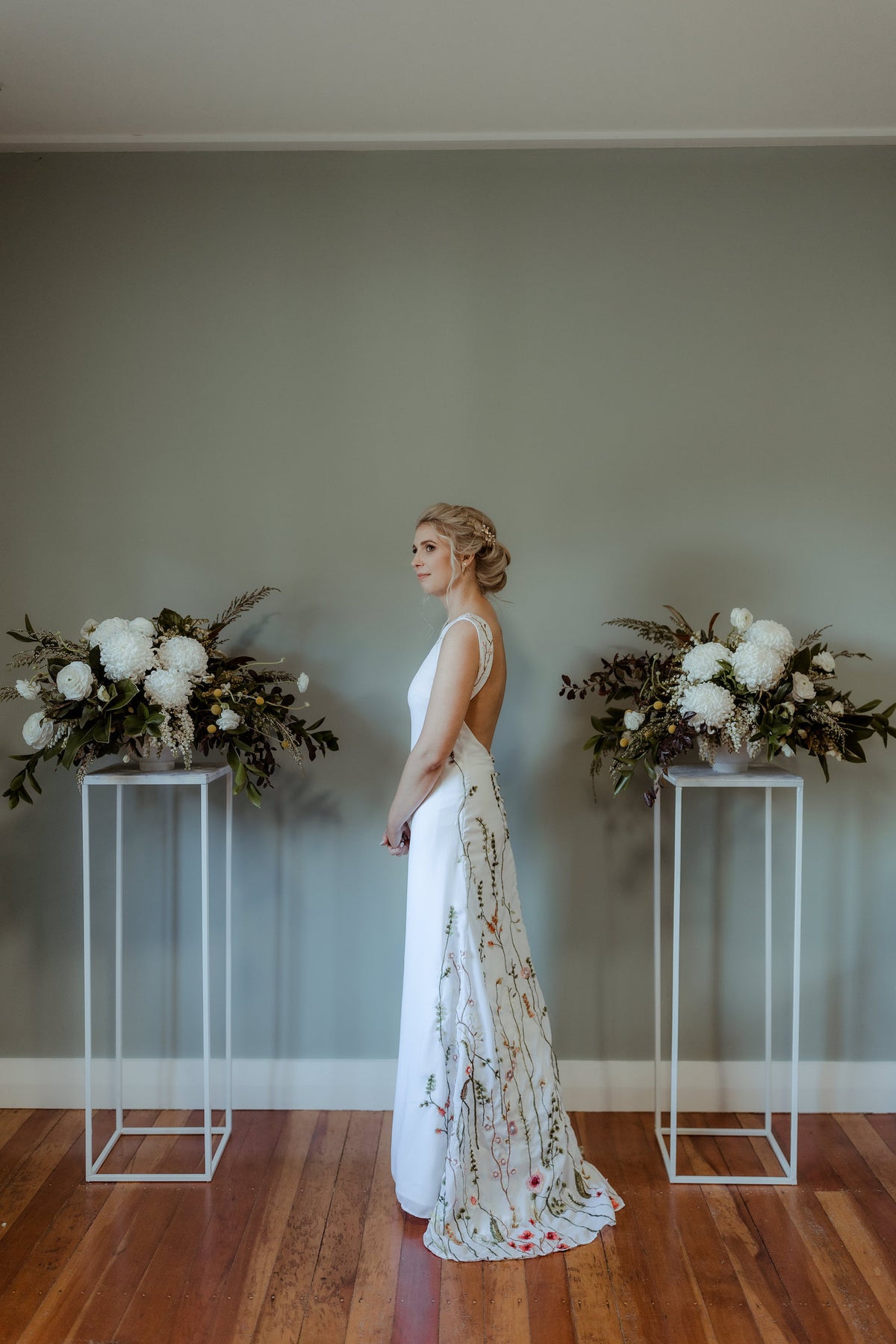 BRIDE-STANDING-BETWEEN-TWO-FLOWER-STANDS