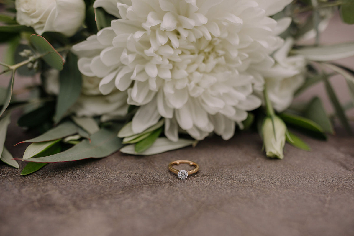 ENGAGEMENT-RING-WITH-WHITE-FLOWER-BEHIND