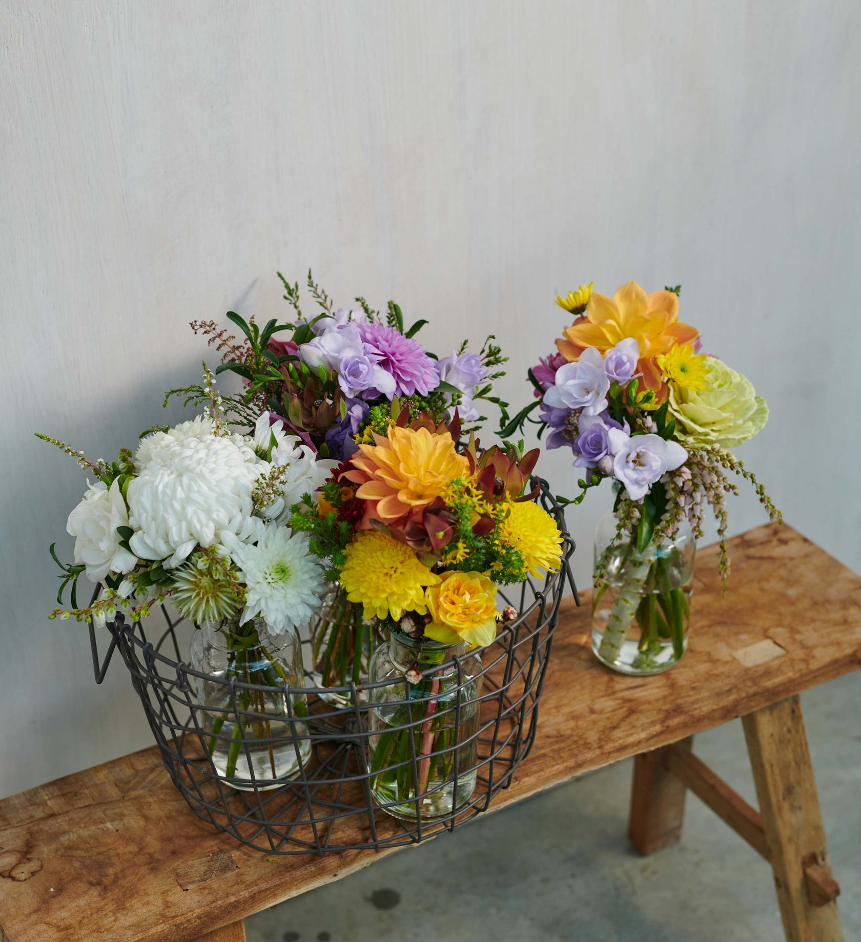SMALL_JAR_BOUQUETS_GROUPED_IN_BASKET_ON_WOODEN_STOOL