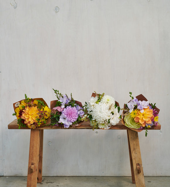 Four-botanics-bright-colourful-medium-flower-bouquets-lined-on-wooden-stool