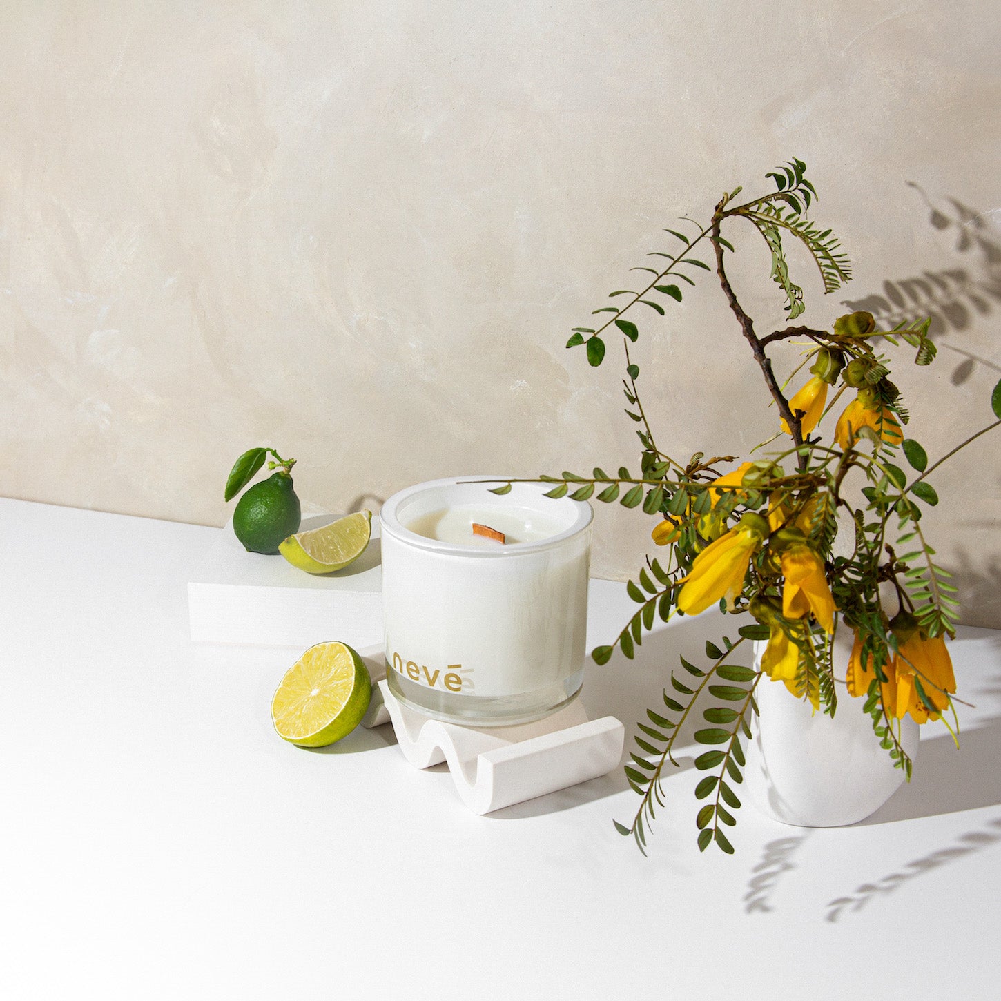 Neve white candle with kowhai blossom branch and limes