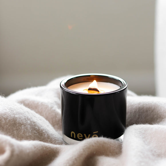 Lit black candle on cosy blanket