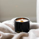 Lit black candle on cosy blanket