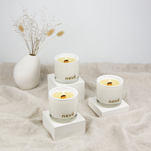 Three white candles on stands with flower vase on linen sheet